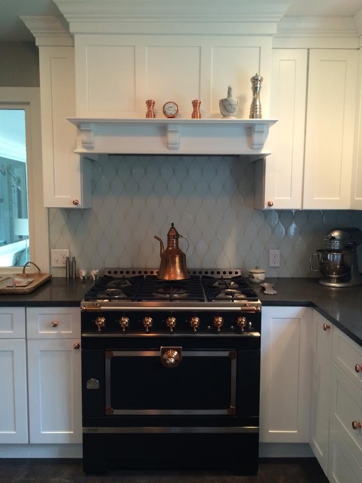 Kitchen with black La Cornue range, copper accents and geometric tile backsplash