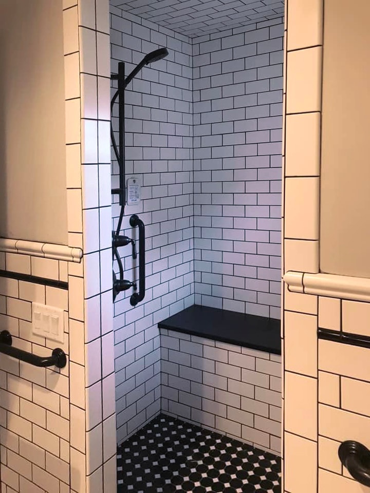 Walk-in shower with white subway tile, black fixtures and mosaic floor