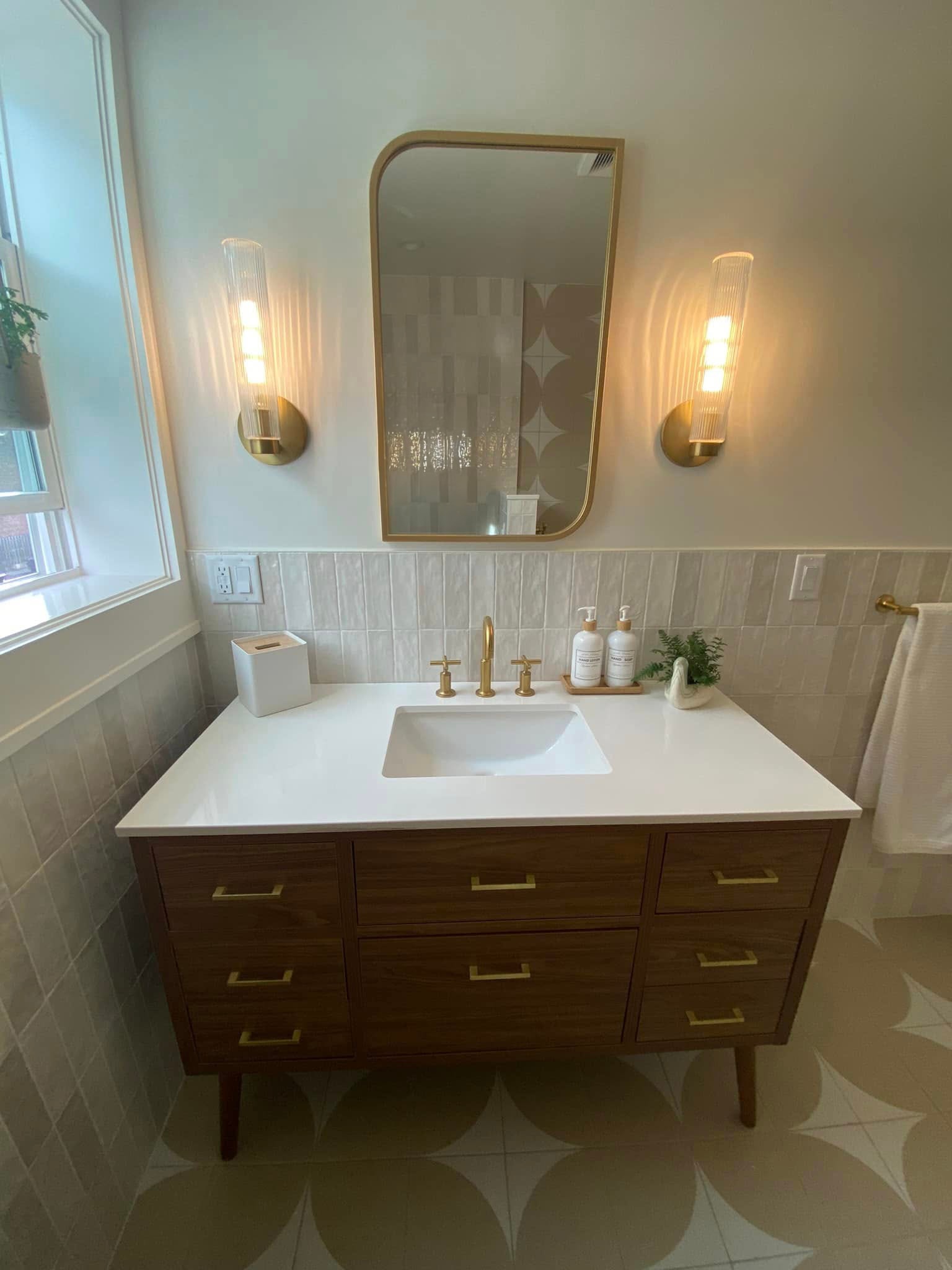 Mid-century modern vanity with gold fixtures, sconce lighting and geometric tile floor