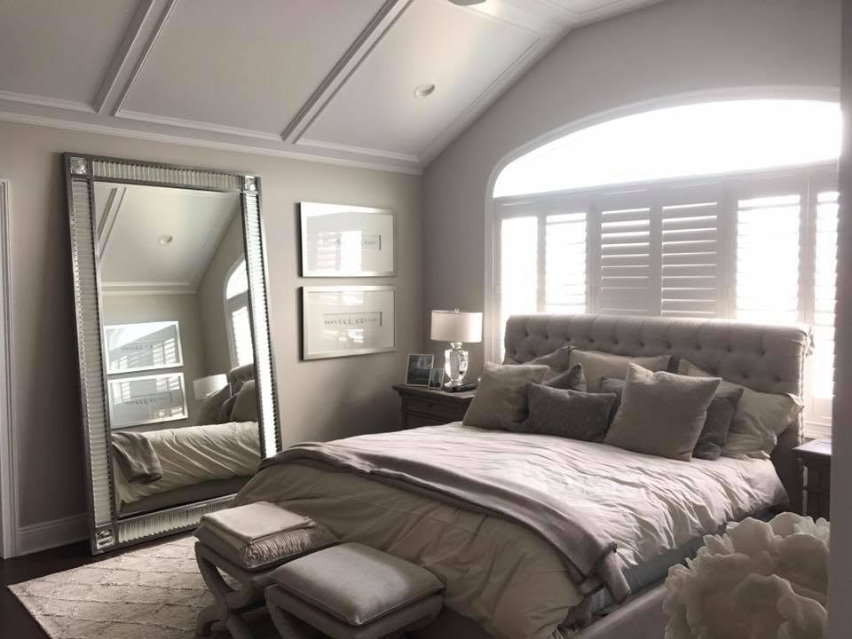 Primary bedroom with tufted headboard, vaulted ceiling and oversized floor mirror