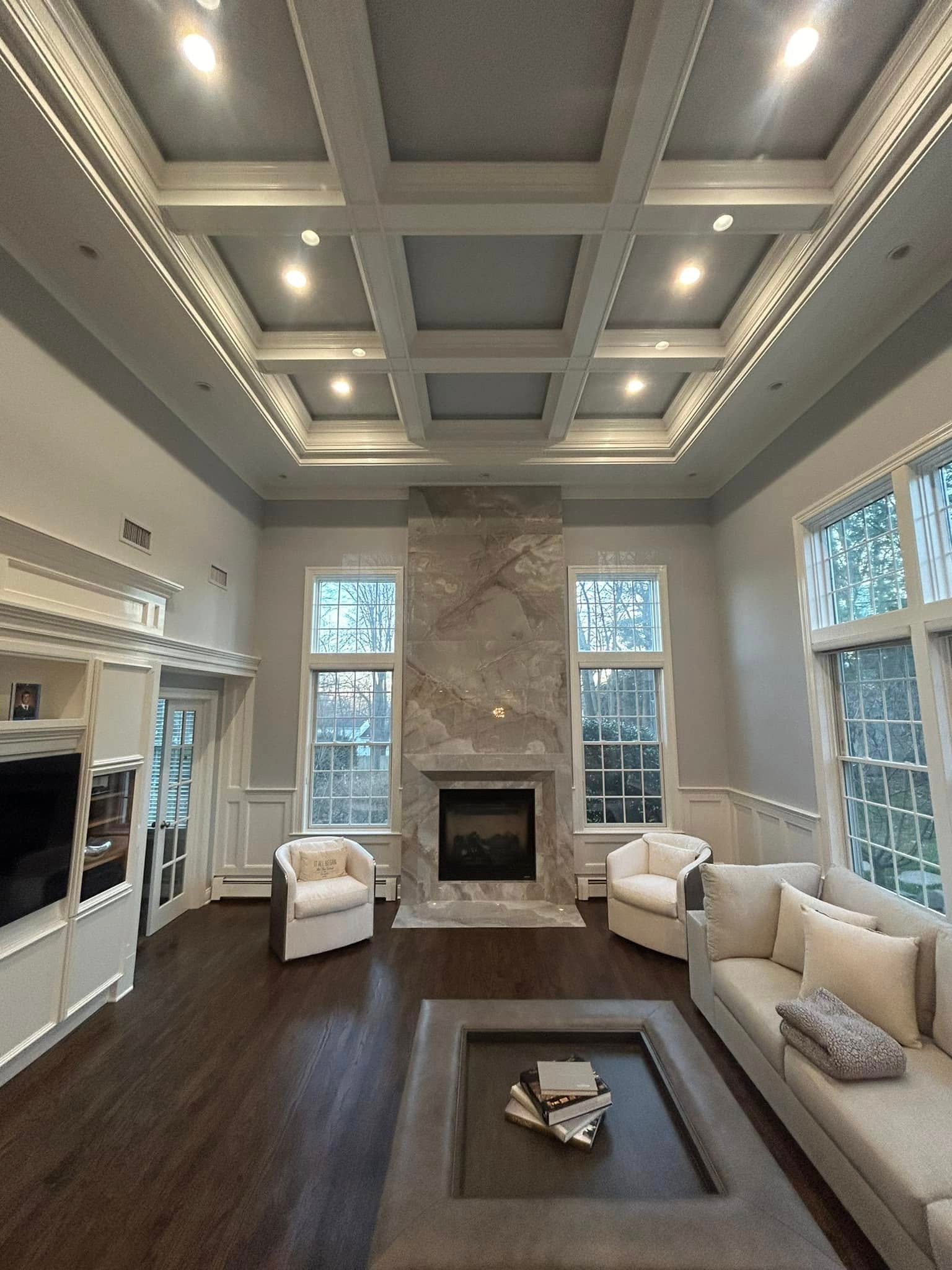Grand living room with coffered ceiling, floor-to-ceiling marble fireplace and tall windows