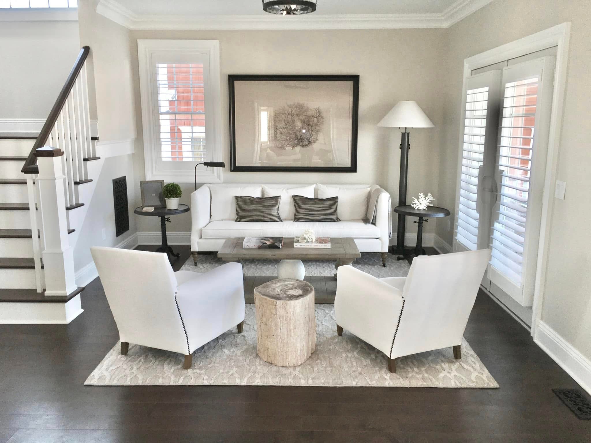 Living room with white sofa, nailhead chairs and large framed botanical art